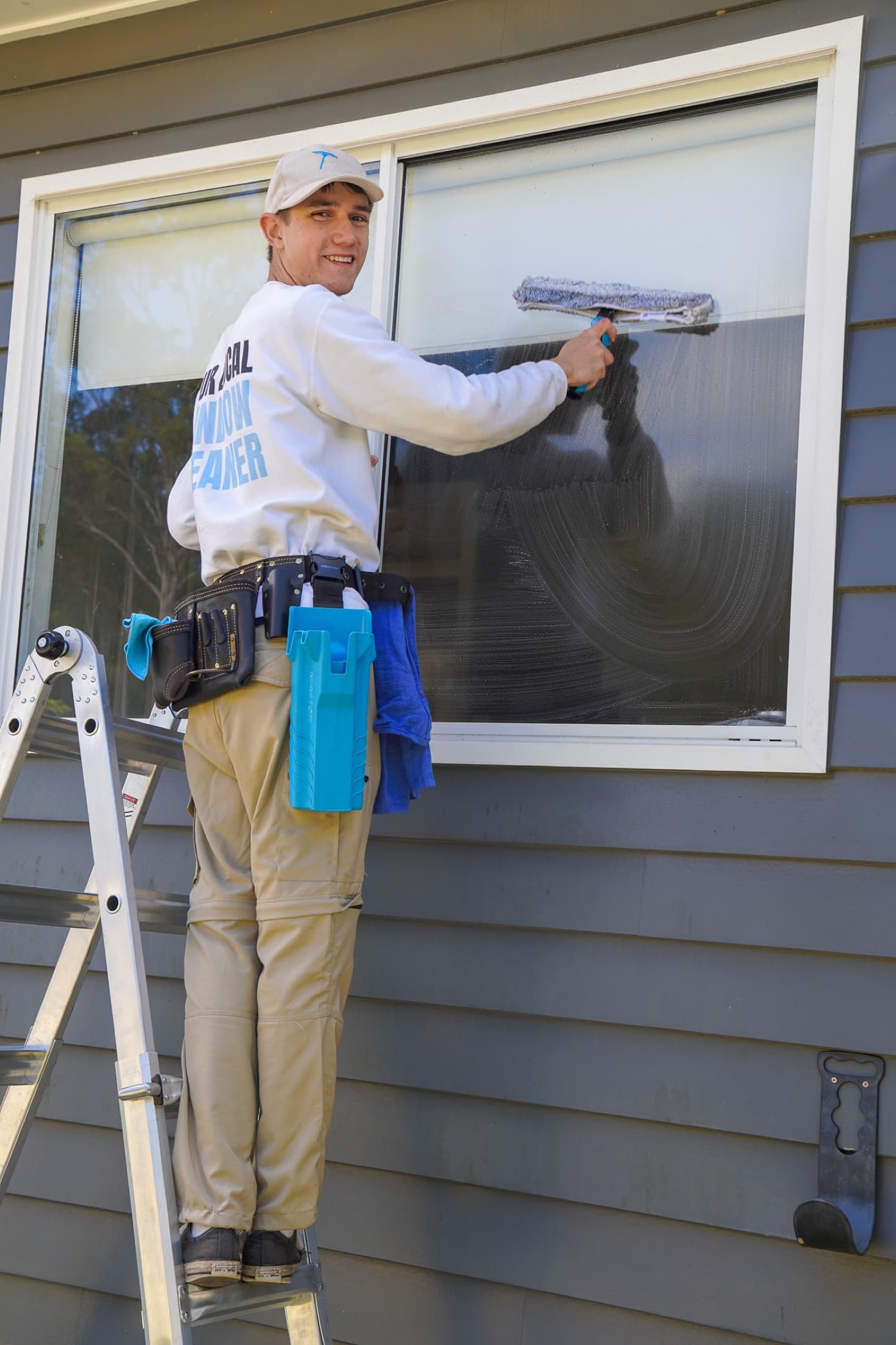 Exterior window clean on a brick home, squeegee on glass