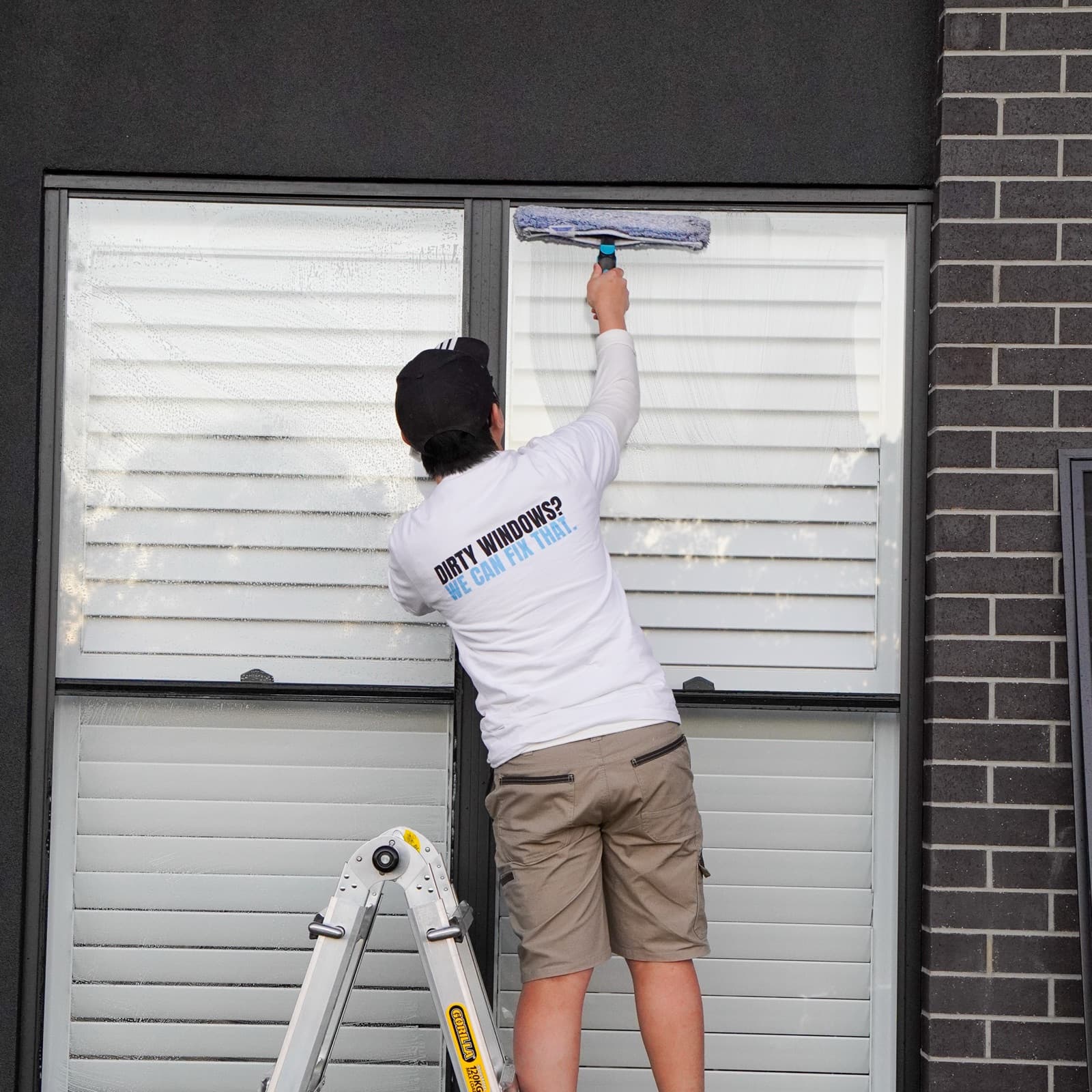 Xavier cleaning the front windows of a brick home in the Lockyer Valley
